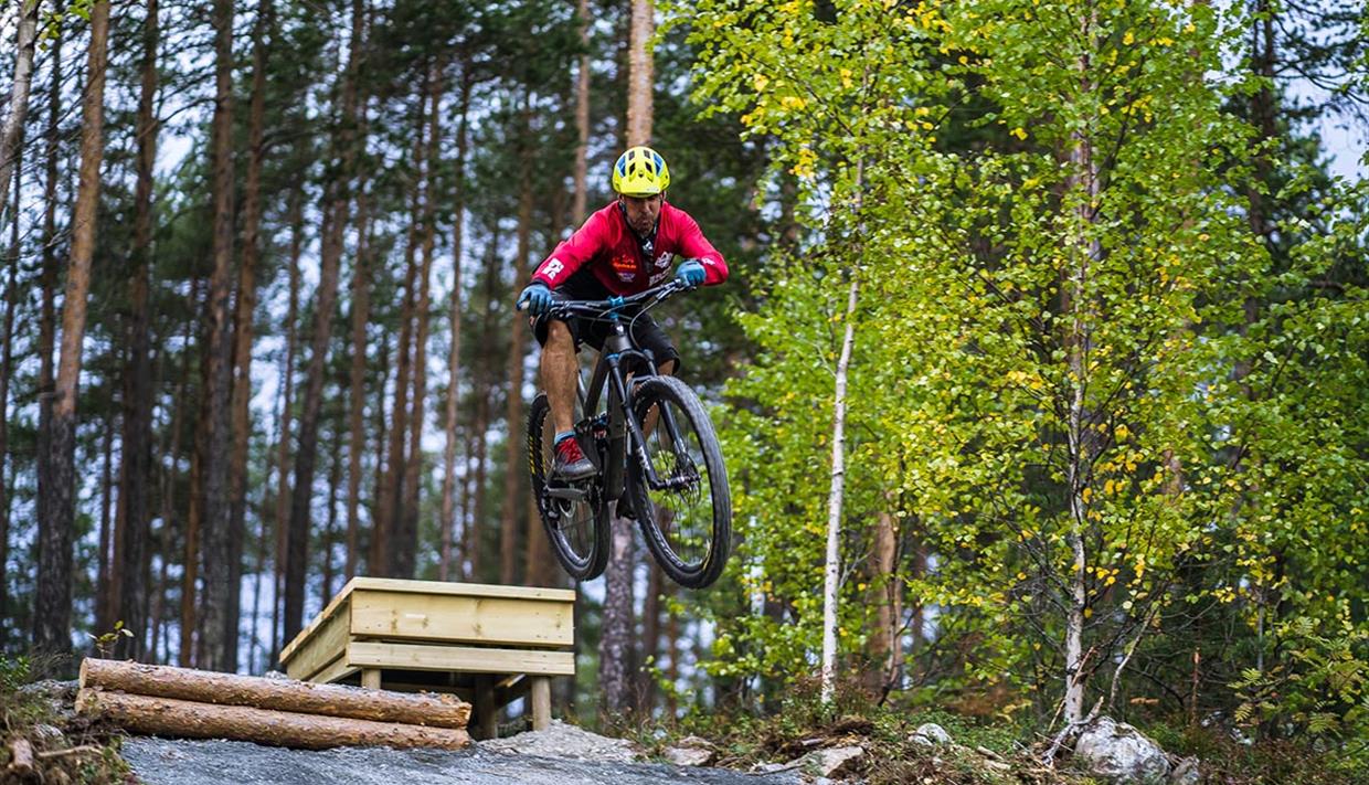 A cyclist jumping over an obstacle in  the terrain cycling area at Leira