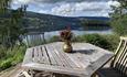 Outdoor teak table with chairs and a view over the lake.