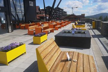 The sun deck of Lodge 900 with modern, colourful tables and benches made of steel and wood.