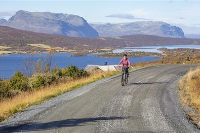 Cyclist on an unsealed mountain road with lakes and mountains in the background
