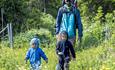 A father and two children on a trail through lush vegetation