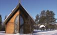 The beautiful small Chapel of Lights from the outside in winter with snow lying on the ground.