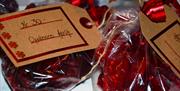 Heimelaga karameller i rødt cellofanpapir, i plastposer med fin julelapp på.
