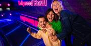 A man and two women at a bowling alley