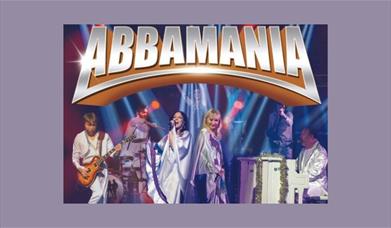 a picture of the tribute act ABBAMANIA, showing two female singers, a man playing guitar, and a second man playing a piano.