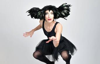 A picture of a woman in a black feathered head piece, a leotard and tutu