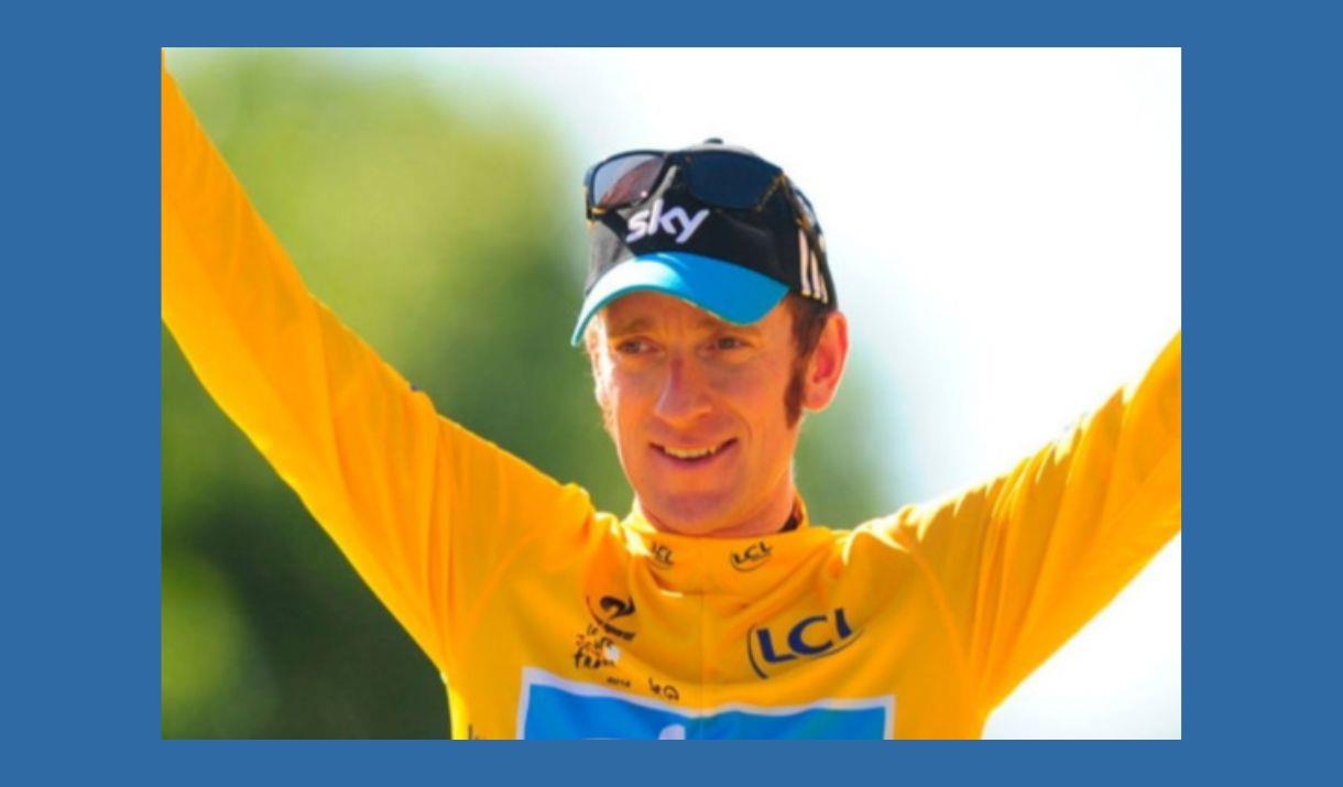 A close-up picture of champion cyclist, Sir Bradley Wiggins, wearing the yellow winner's jersey of the Tour de France, and raising his arms in victory