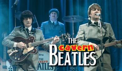 A picture of tribute band, The Cavern Beatles, on a stage and playing instruments and singing
