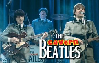 A picture of tribute band, The Cavern Beatles, on a stage and playing instruments and singing