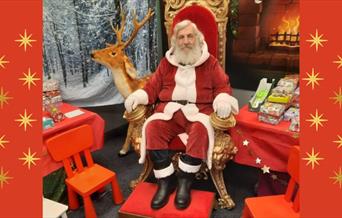 A picture of Santa Claus sitting in his grotto