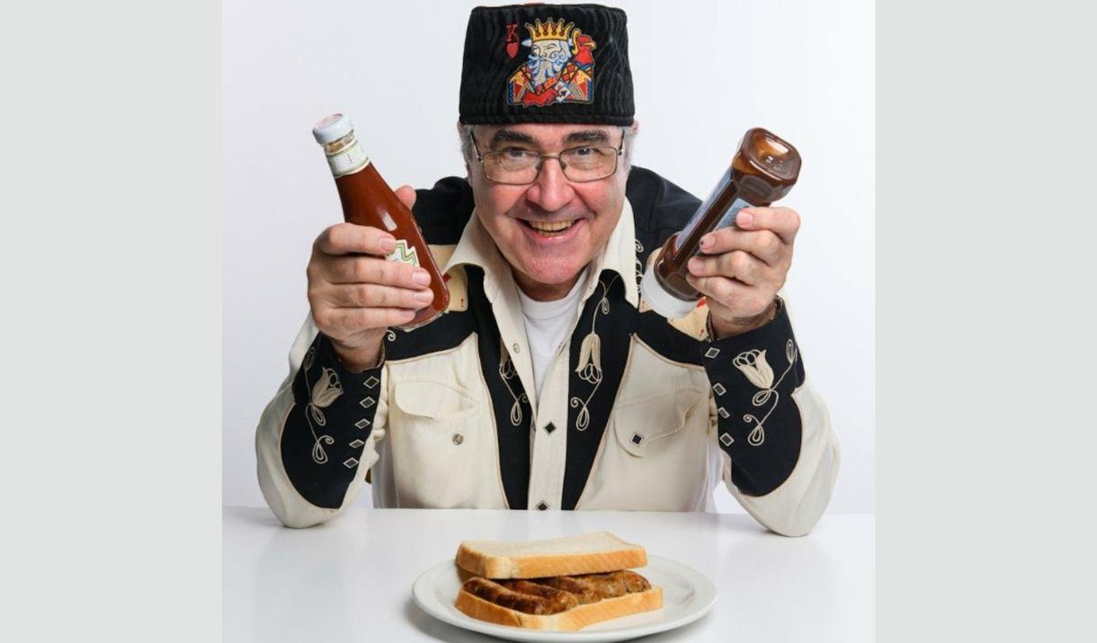 A picture of comedian Danny Baker, wearing a blue fez with an eye embroidered onto it