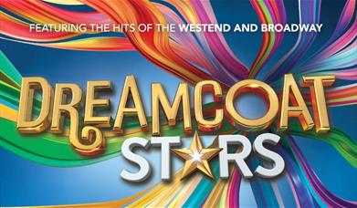 A rainbow background with the words Dreamcoat Stars in gold and white