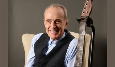 A picture of musician Francis Rossi, with his guitar on a stand next to him