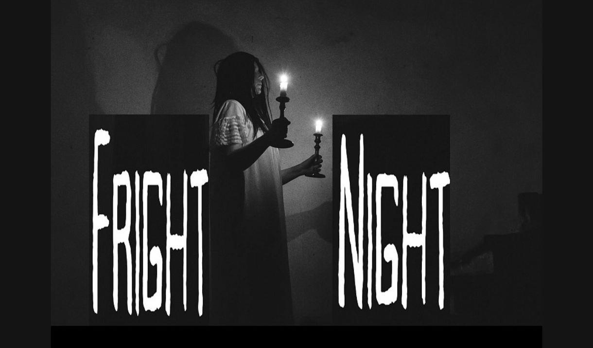 A picture of a woman in a long white dress, in a dark room, holding two lit candles. The words "Fright" and "night" are on either side of her