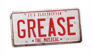 A picture of an American vehicle licence plate with "Grease" in big letters in the middle, and "The Musical" in smaller letters underneath.