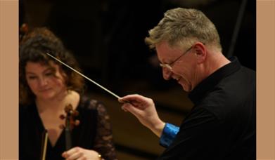 A picture of Halle Orchestra conductor Stephen Bell, with a violinist to his left