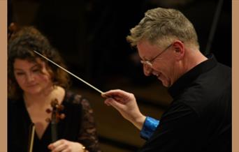 A picture of Halle Orchestra conductor Stephen Bell, with a violinist to his left