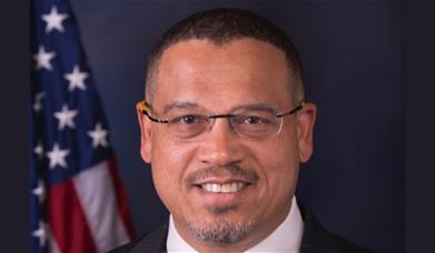 A close-up picture of the face of Minnesota Attorney General and U.S. Congressman, Keith Ellison. There is an American flag in the background, to the 