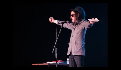 A picture of poet Dr John Cooper Clarke, on stage