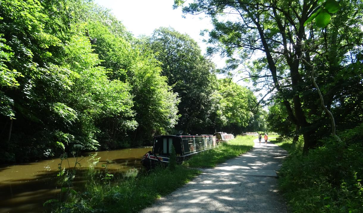 View from the towpath with trees and barge on the canal