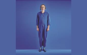 A picture of the comedian Paul Foot, dressed in blue, against a blue background
