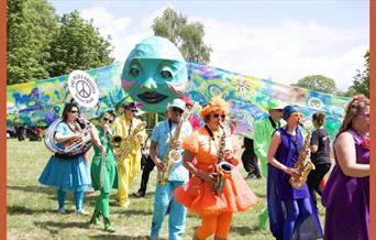 A picture of musicians in colourful clothing, in a park