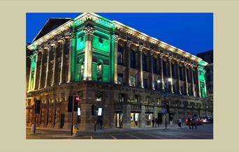 A picture of St. George's Hall, at night, with the corners of the building illuminated by green light