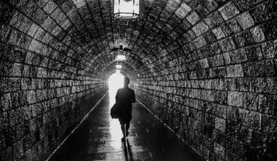 A person walking under a tunnel. 