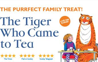 A picture of a tiger and a little girl sitting together at a table with tea things on it