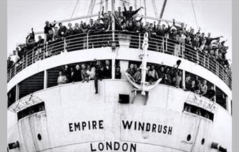 A black and white photograph of the ship Empire Wimdrush, with crowds of people waving from the top two decks