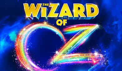 A poster advertising the show. The words "the wizard of" are done in yellow bricks, and the word "oz" is done in rainbow colours.