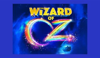 A poster advertising the show. The words "the wizard of" are done in yellow bricks, and the word "oz" are done in rainbow colours. A little house is s