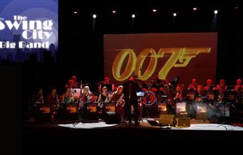 A picture of the Swing City Big Band on stage, with the James Bond 007 logo on a screen behind them