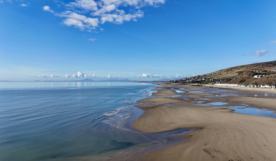 A sunny day, during low tide, the beach is vast and sandy