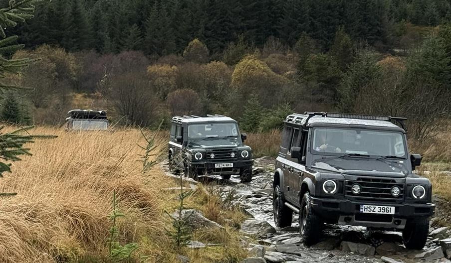 Land Rovers in convoy on rocky terrain.