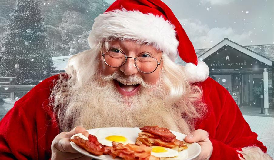 Santa holding plate of bacon and eggs with Elan Valley Visitor Centre in background