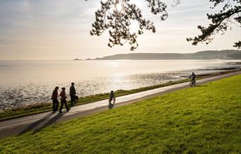 Cyclist and walkers on Coast Path at Blackpill at sunrise