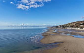 A sunny day, during low tide, the beach is vast and sandy