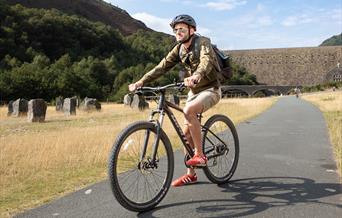 Man cycling in front of a dam at Elan Vlaley
