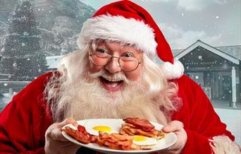 Santa holding plate of bacon and eggs with Elan Valley Visitor Centre in background