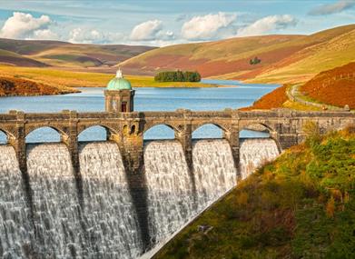 Water pouring over Craig Goch dam in the Elan Valley with autumn bracken on the hills