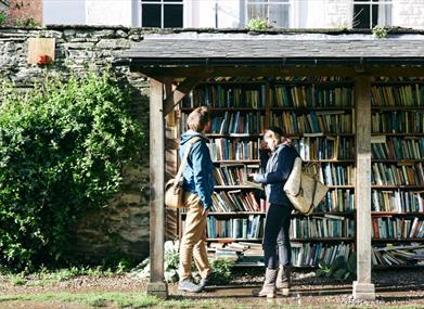 Two people browsing the outdoor honesty bookshelves in Hay-on-Wye