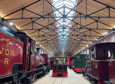 Steam locomotives on display under a glass roof at the Vale of Rheidol Railway in Aberystwyth