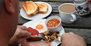Cooked breakfast at Hafren Forest Hideaway enjoyed outdoors on a picnic bench, Mid Wales group accommodation