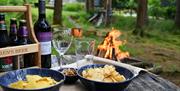 Outdoor fire pit at Hafren Forest Hideaway with snacks, beer, and wine, ideal for groups after hiking, biking, or paddle sports in Mid Wales