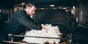 A craftsperson is putting wool into the carding machine.