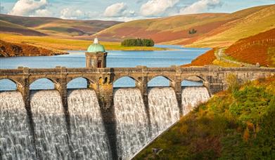 Water pouring over Craig Goch dam in the Elan Valley with autumn bracken on the hills