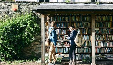 Two people browsing the outdoor honesty bookshelves in Hay-on-Wye