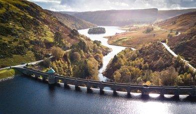 Elan Valley dam with water cascading over Victorian stonework into the river below