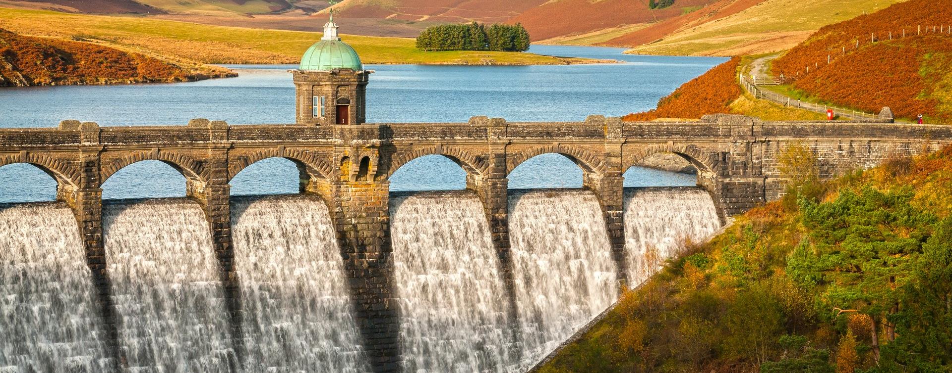 Water pouring over Craig Goch dam in the Elan Valley, with autumn bracken on the hills behind